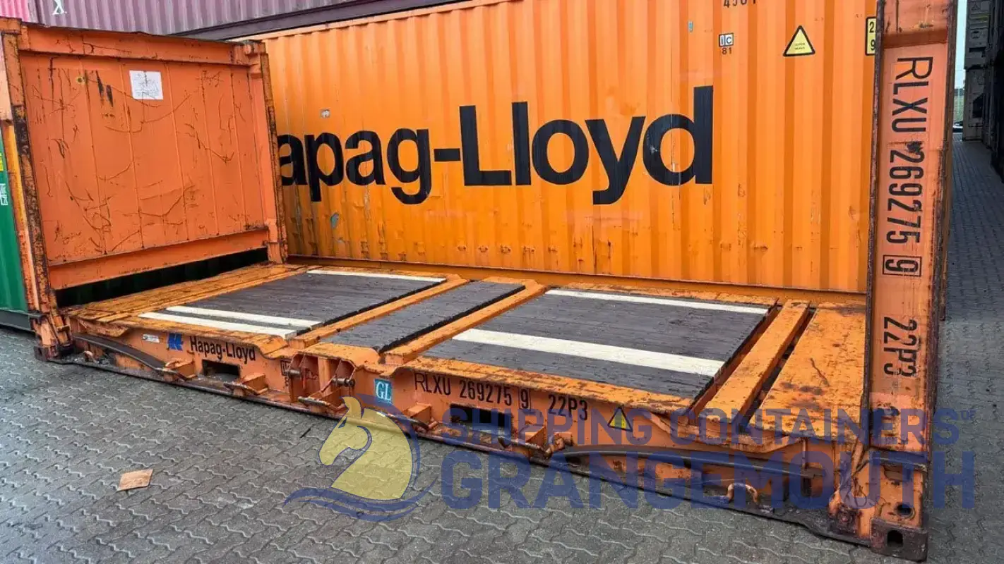 An open shipping container with Hapag-Lloyd branding, resting on a pavement, showing wood flooring inside.