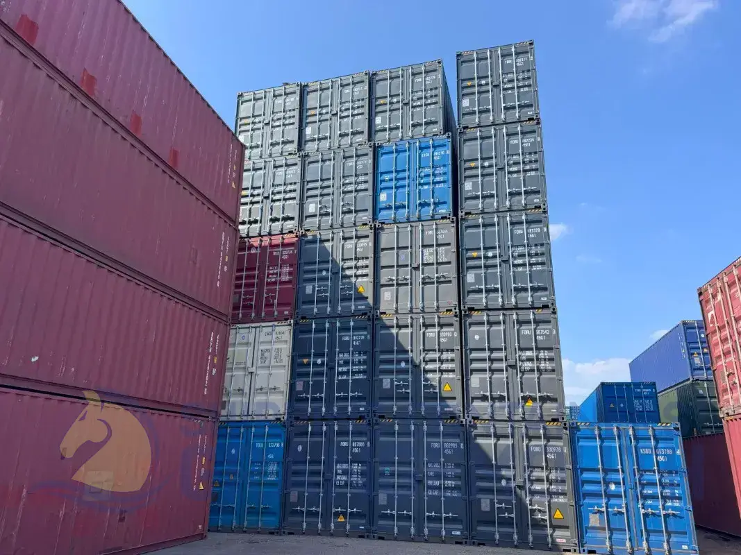 A stack of shipping containers in various colors under a clear blue sky.