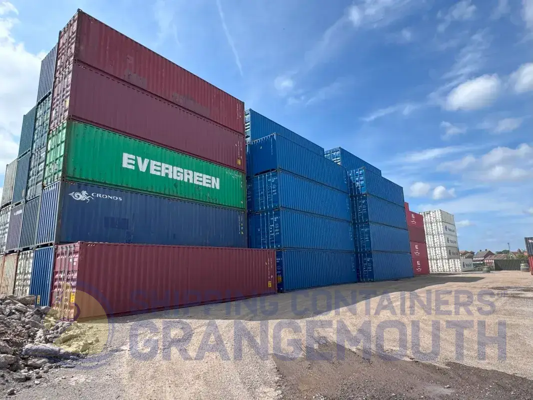 A stack of colorful shipping containers under a blue sky at a storage facility.