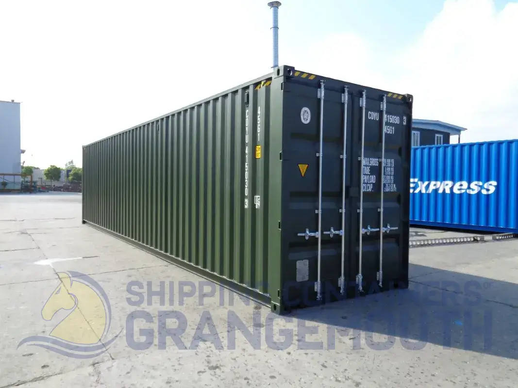 A large green shipping container stands on a concrete area, with another blue container partially visible in the background.